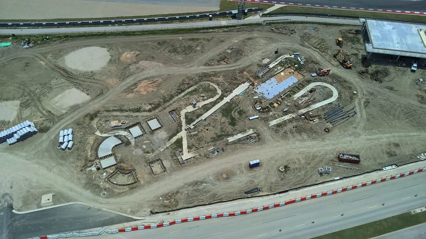 Aerial view of graded earthwork, staged culvert pipe and excavation equipment on a site under development